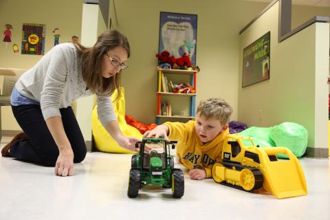 an ABA therapist with a boy who is pushing a truck