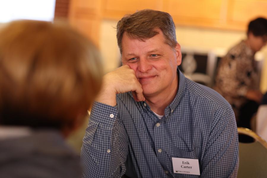 Photo of Erik Carter smiling listening to someone at a B2B event