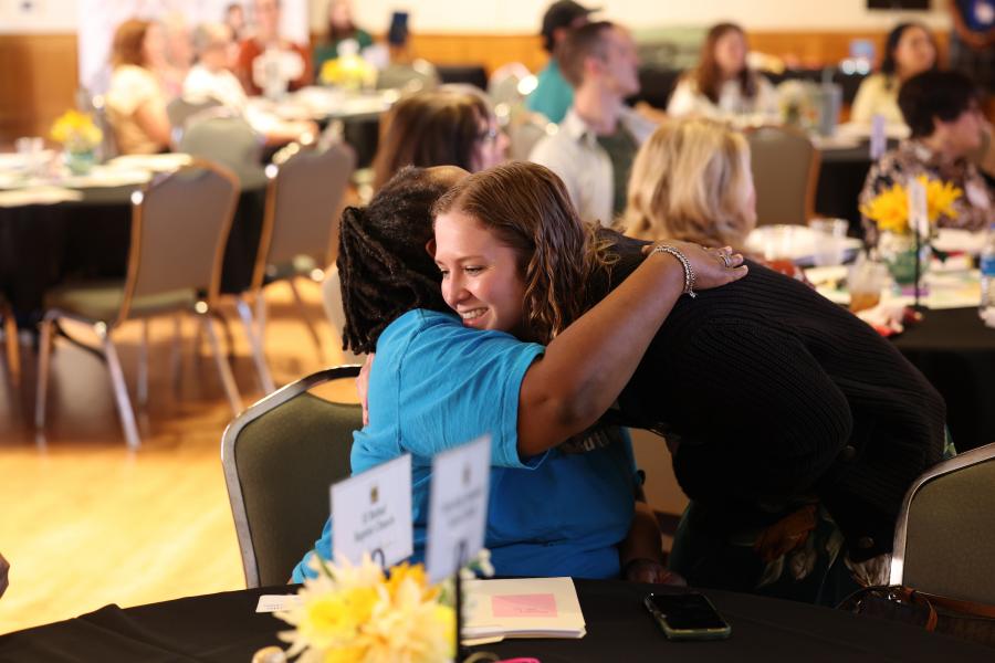 Photo of Elyse McMullen smiling in an embrace with a fellow Bridges to Beloning cohort member.