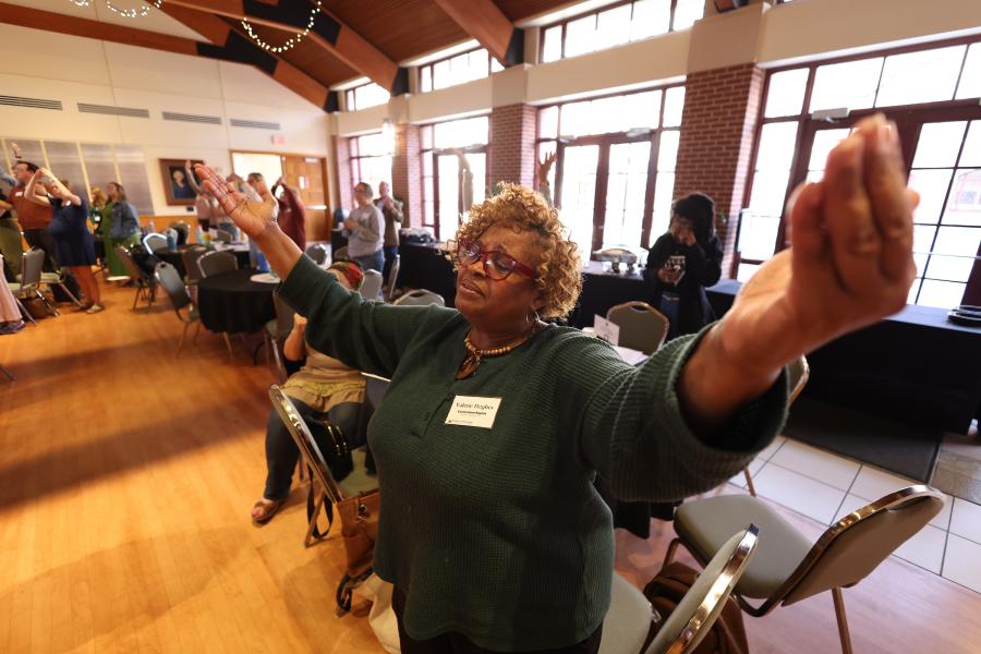 Photo of woman worshipping with arms raised at the Bridges to Belonging gathering.