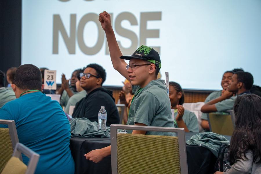 Photo of student attending Oso Able conference with fist pumped in the air alongside his smiling peers.