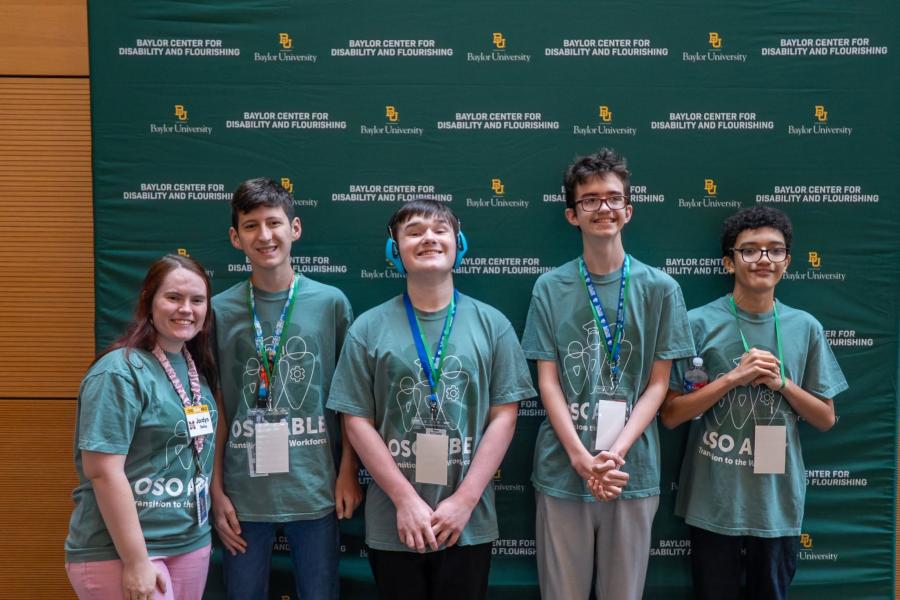 Students posing in front of photo backdrop at Oso Able Conference.